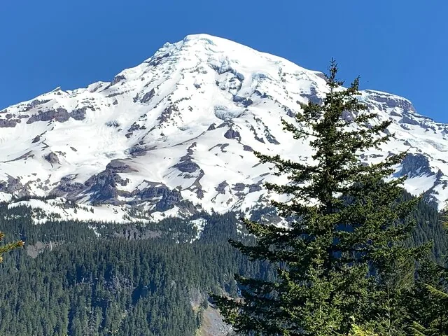 Vista de cerca del Monte Rainier cubierto de nieve contra un cielo azul.
